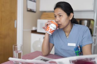 Trött sjuksköterska dricker kaffe i personalrummet