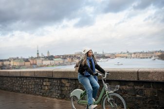 Ung kvinna på cykel med Gamla stan i bakgrunden