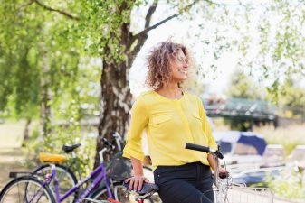 Glad kvinna i gul blus på cykel.