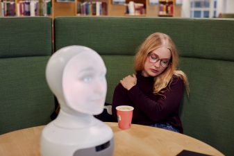 Ung kvinna på bibliotek med robot