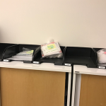 Patientpapper ligger i plastmappar i olika fack på en bänk.