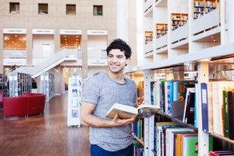 Young man holding book in library