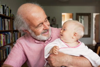 Older man holding grandchild and smiling