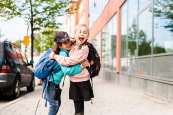Glada skolbarn håller om varandra på gatan