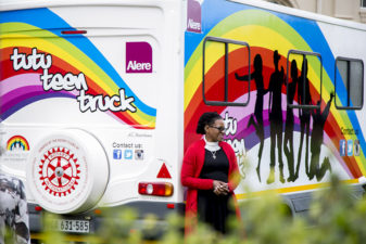 Kvinna står utanför den regnbågdsfärgade bussen Tutu Teen Truck
