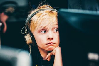 Pojke med hörlurar sitter framför datorskärm