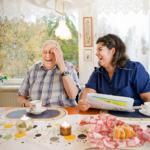 Äldre man skrattar tillsammans med medarbetare från hemtjänsten