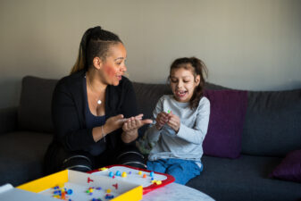 Flicka med utvecklingsstörning talar med tecken med sin mamma